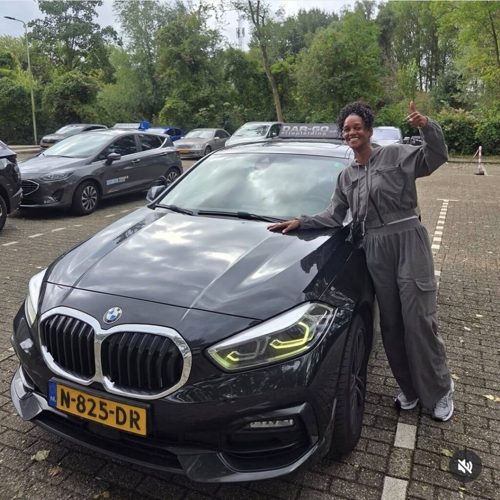 Geslaagde leerling poseert trots naast BMW bij DAR-GO Rijopleiding na het behalen van rijbewijs Geslaagde leerling poseert trots naast BMW bij DAR-GO Rijopleiding na het behalen van rijbewijs