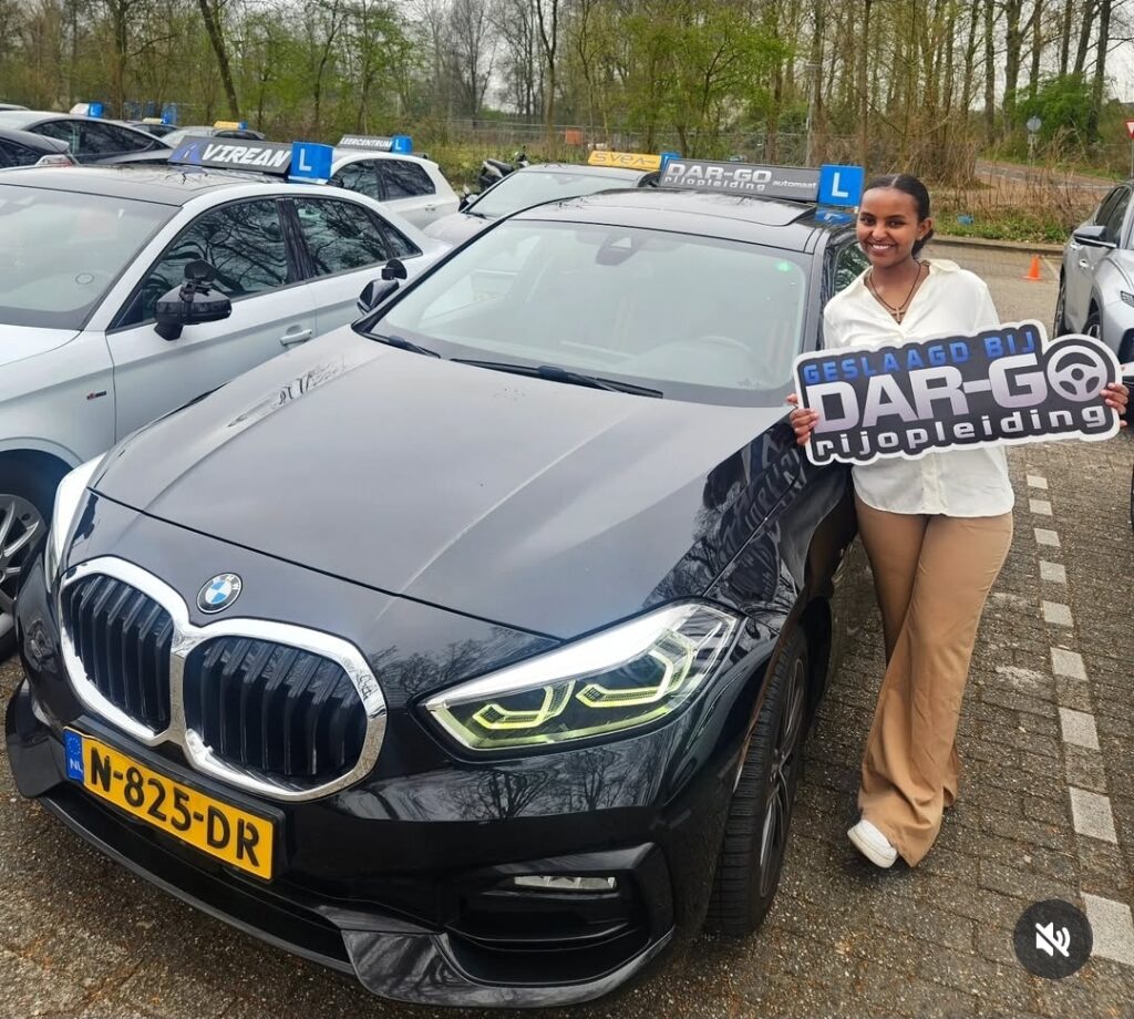Geslaagde leerling toont DAR-GO rijschool certificaat bij BMW rijlesauto in Rotterdam Geslaagde leerling toont DAR-GO rijschool certificaat bij BMW rijlesauto in Rotterdam