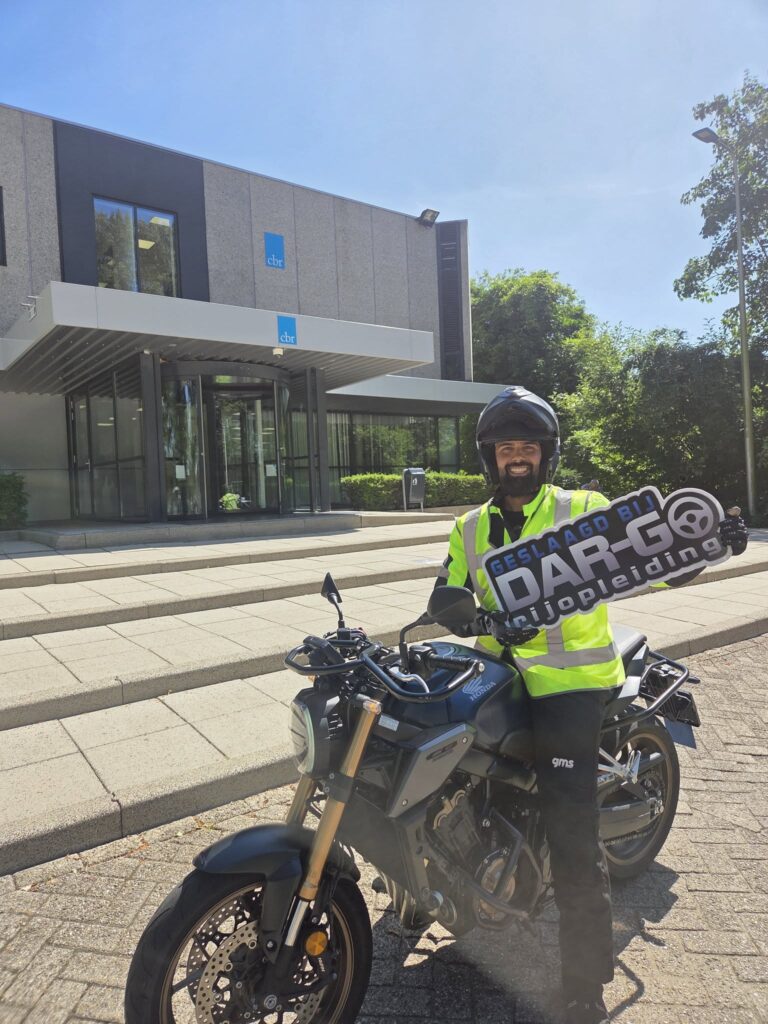 Geslaagde motorrijder van DAR-GO Rijopleiding poseert met Honda motor voor CBR gebouw Rotterdam Geslaagde motorrijder van DAR-GO Rijopleiding poseert met Honda motor voor CBR gebouw Rotterdam