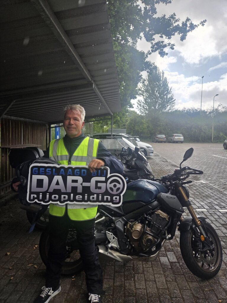 Geslaagde motorrijder van DAR-GO Rijopleiding poseert met motor na het behalen van rijbewijs Geslaagde motorrijder van DAR-GO Rijopleiding poseert met motor na het behalen van rijbewijs