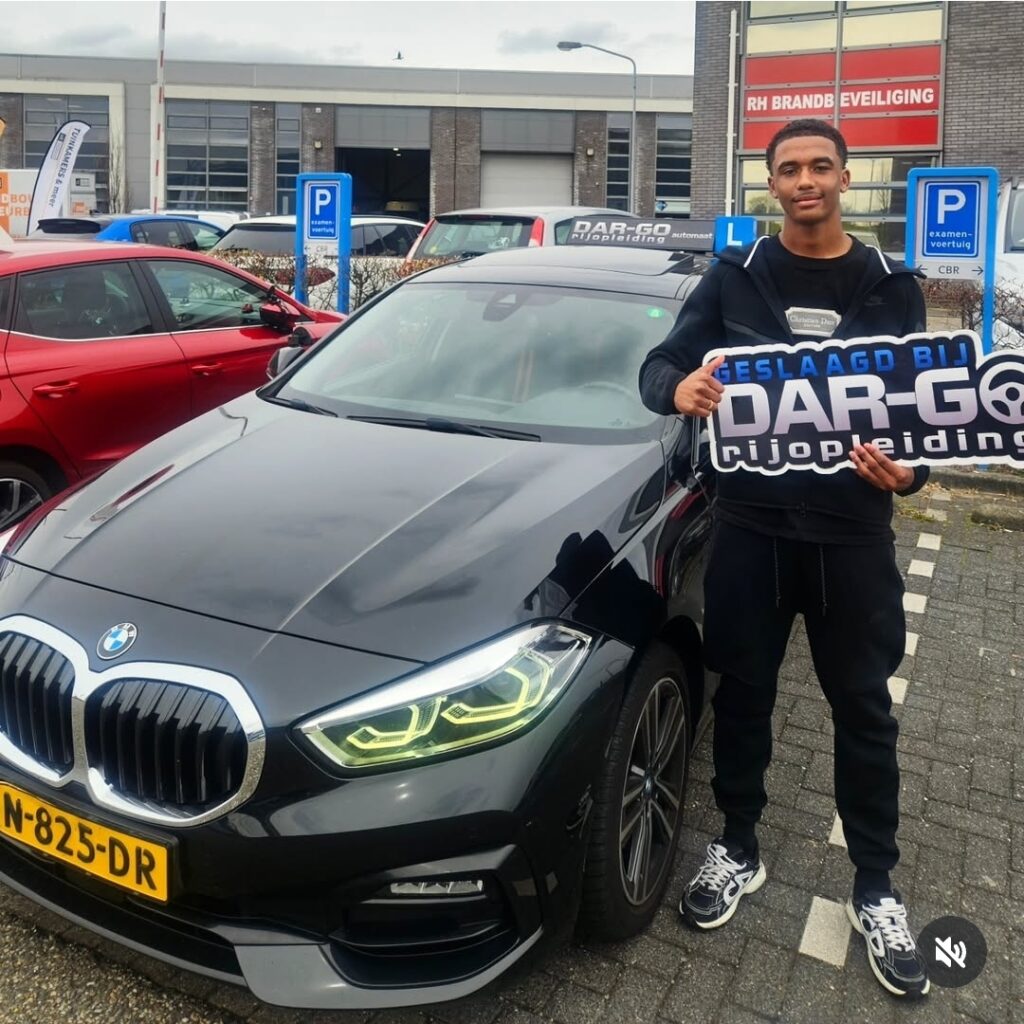 Geslaagde rijleerling poseert trots met DAR-GO banner na het behalen van zijn rijbewijs in Rotterdam Geslaagde rijleerling poseert trots met DAR-GO banner na het behalen van zijn rijbewijs in Rotterdam