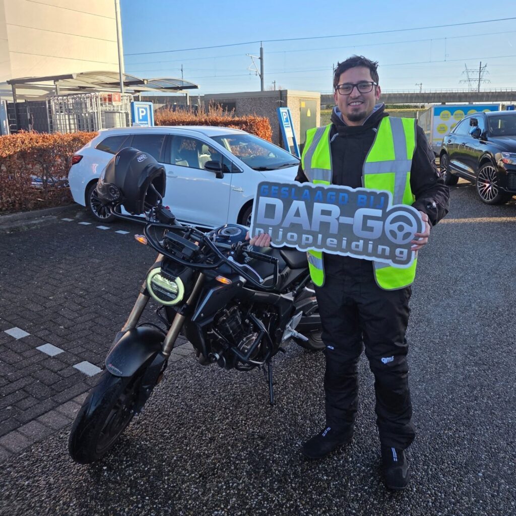 Geslaagde student toont DAR-GO rijschool certificaat naast motor na succesvol motorrijexamen