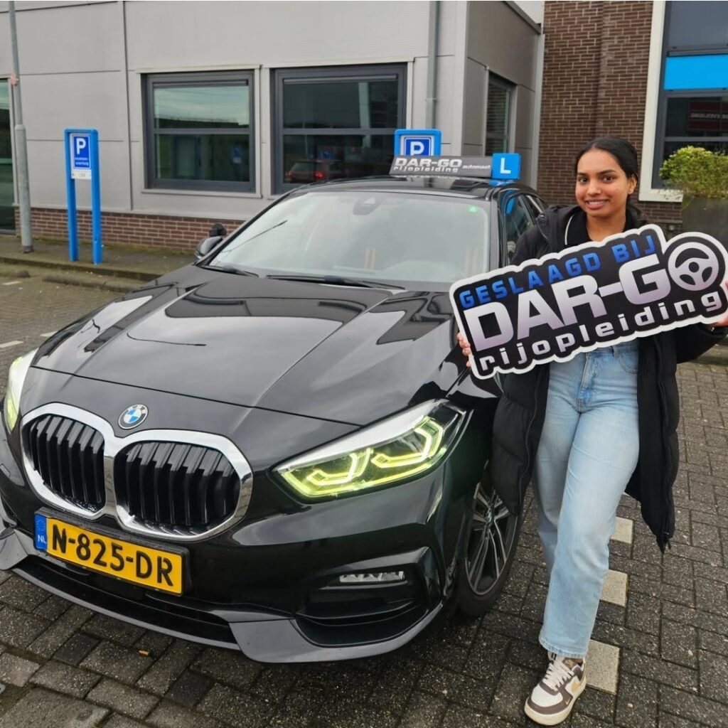 Geslaagde student van DAR-GO Rijopleiding toont geslaagd certificaat naast BMW rijschoolauto Geslaagde student van DAR-GO Rijopleiding toont geslaagd certificaat naast BMW rijschoolauto