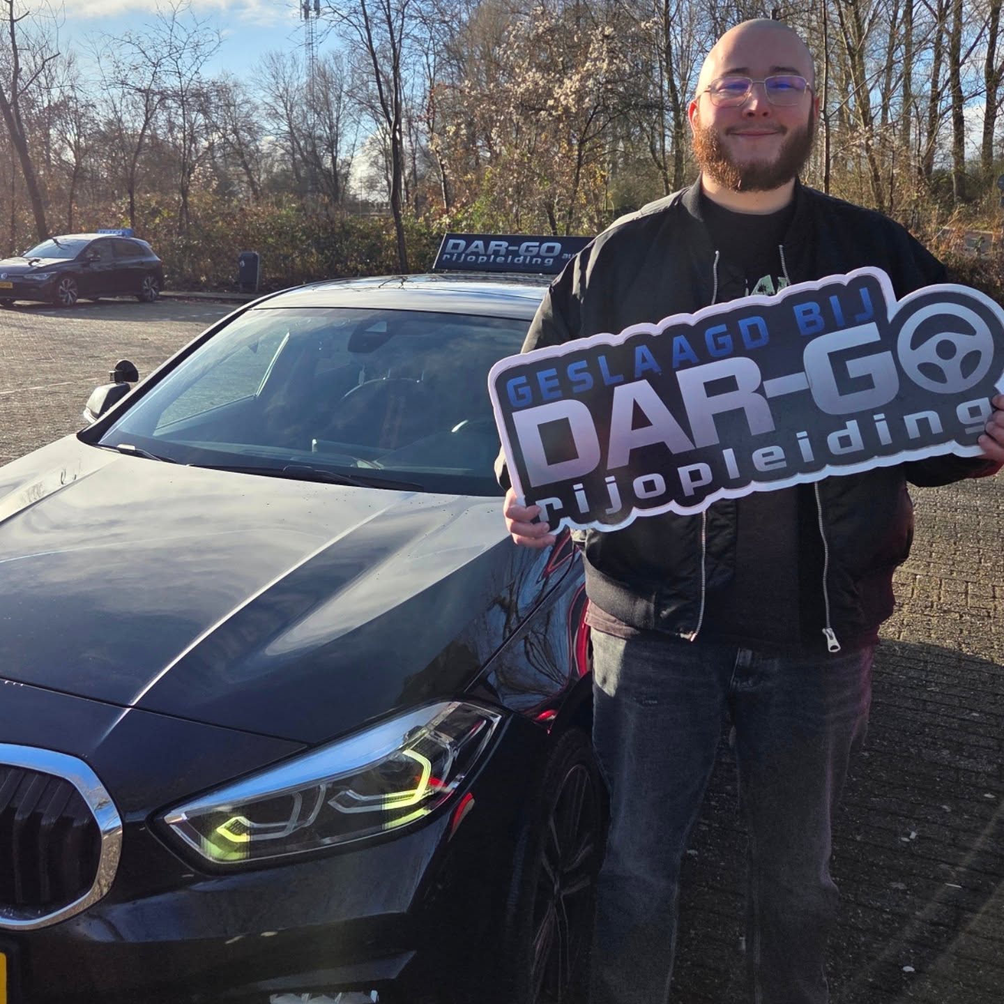 Rijschool Capelle aan den IJssel ✔️ Direct Starten 1 Geslaagde student van DAR-GO Rijopleiding toont trots zijn rijbewijs certificaat naast BMW auto