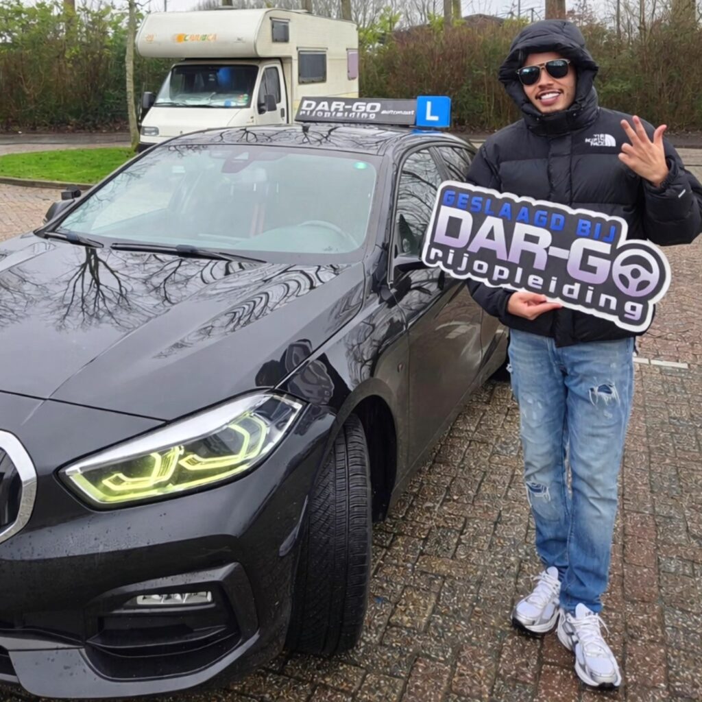 Geslaagde student van DAR-GO rijschool toont trots zijn rijbewijs bij auto met L-bord
